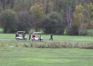 two golf carts waiting while a golf takes a shot